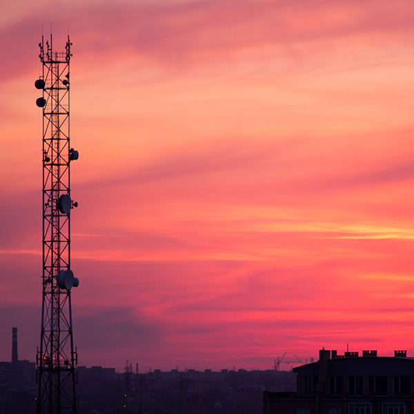 View of sunset in a downtown area with a radio tower in the foreground