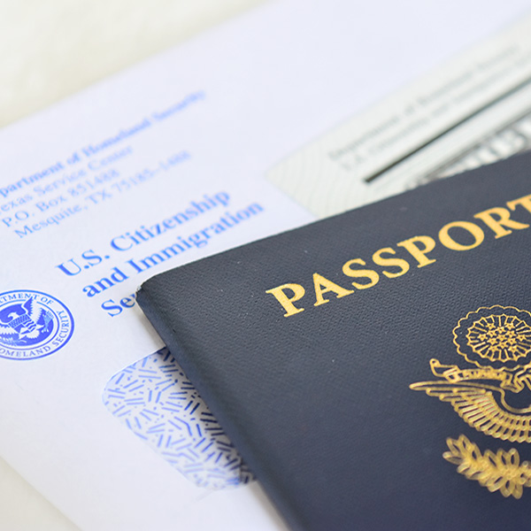 Close up of a U.S. Citizenship and Immigration Services envelope with a passport sitting on top of it