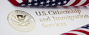 Close up view of the U.S. Citizenship and Immigration Services logo between two United States flags