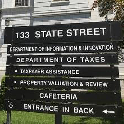 Daytime view of the Department of Taxes sign outside the Vermont State House in Montpelier