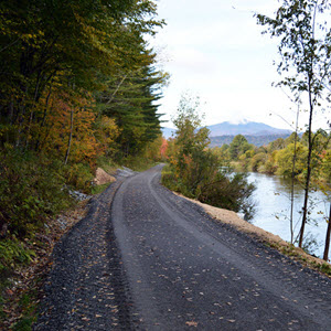 Daytime view of a railroad right of way converted to a trail in Vermont with mountains in the background.