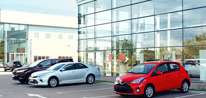 Daytime view of an auto dealership with three cars parked outside